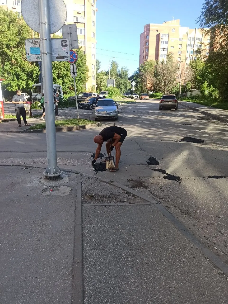 Местные жители и активисты заделывают ямы в асфальте на улице Лукачева в Тольятти; прохожие и водители выражают благодарность.